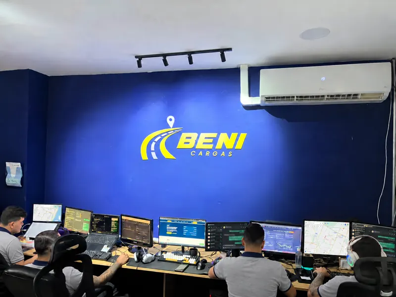 Equipe da Beni Cargas trabalhando na central de atendimento, com o logo da empresa na parede